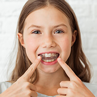 ortho-clear-aligners young girl pointing at her braces