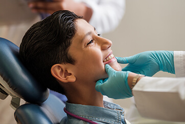 ortho-when-to-schedule young boy holding his jaw in pain